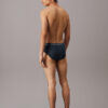 Modelo de espaldas con slip Calvin Klein Cotton Stretch QY5 en azul oscuro, mostrando ajuste trasero