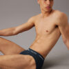 Modelo sentado con slip Calvin Klein Cotton Stretch QY5 en azul oscuro, vista lateral