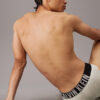 Modelo sentado con slip Calvin Klein Intense Power QTK en gris, vista lateral