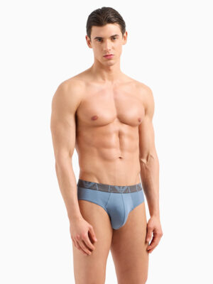 Modelo vistiendo slip azul claro Emporio Armani 4F715 con banda elástica y logotipo gris