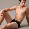 Modelo recostado usando slip Calvin Klein Micro Stretch en negro, con cinturilla distintiva