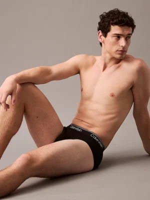 Modelo recostado usando slip Calvin Klein Micro Stretch en negro, con cinturilla distintiva