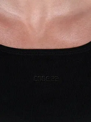 Modelo de perfil luciendo la camiseta de tirantes negra Code 22 Train, resaltando el corte entallado y la caída recta