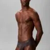 Hombre llevando calzoncillo slip Calvin Klein CK Black de talle bajo en color marron oscuro carbón
