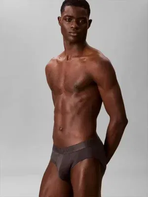 Hombre llevando calzoncillo slip Calvin Klein CK Black de talle bajo en color marron oscuro carbón