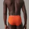 Vista posterior del slip ligero Calvin Klein en color naranja, destacando el diseño limpio sin fricción en el muslo.