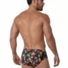 Vista frontal de bañador slip con estampado de piñas e hibiscos sobre fondo oscuro — BLU2553 Beachbrief Olaf Benz