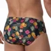 Vista frontal de bañador slip con estampado de piñas e hibiscos sobre fondo oscuro — BLU2553 Beachbrief Olaf Benz
