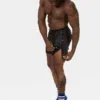 Modelo con short Fuad negro royal de Barcode Berlin abriendo los botones laterales