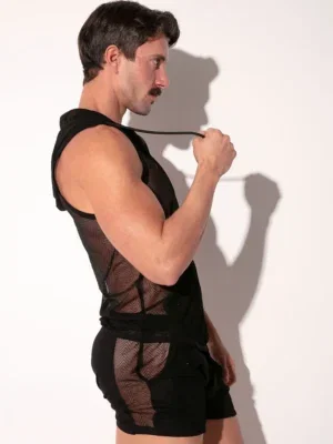 Hoody Rock sin mangas: capucha, cremallera frontal y bolsillo canguro en tul Silueta poco habitual dentro del catálogo: una camiseta sin mangas con capucha completa, cordones ajustables, cremallera frontal en V y bolsillo canguro, construida en el tul Rock con patrón de espigas tono sobre tono y micro-apliques negros con acabado brillante. La capucha, el bolsillo y la banda inferior van en tejido liso opaco — el resto del cuerpo es tul. Detalles clave Capucha completa con cordones ajustables y remates negros en los extremos. Cremallera frontal corta en V — la prenda se pasa por la cabeza, no se abre por completo. Bolsillo canguro frontal y banda inferior en tejido liso opaco. Cuerpo y espalda en tul con patrón de espigas tono sobre tono y micro-apliques negros con acabado brillante. Logo Code 22 en relieve en la espalda, sobre la banda lisa de hombros. Composición y cuidado 86% poliamida, 14% elastano. Lavar a máquina a máximo 30 °C. No usar lejía. No meter en secadora. Planchar a temperatura suave (máx. 110 °C). No lavar en seco. Preguntas frecuentes ¿Cómo se pone esta prenda? Se mete por la cabeza. La cremallera frontal es corta, en V — sirve para abrir más o menos el escote, no para abrir la prenda entera como un hoody con cierre completo. ¿Cómo es el tul? El mismo tejido del resto de la línea Rock: tul ligero con patrón de espigas tono sobre tono y micro-apliques negros con acabado brillante. Cuerpo y espalda van en tul; capucha, bolsillo canguro y banda inferior van en tejido liso opaco a contraste. ¿La capucha se puede llevar puesta? Sí. La capucha es completa y forrada, con cordones ajustables. Se puede llevar caída sobre la espalda — donde añade volumen visual al hombro — o subida. ¿Qué talla pido en Code 22? La talla habitual funciona. El patronaje de Code 22 es predecible entre colecciones y queda más cercano al cuerpo que una camiseta sin mangas estándar, sin compresión incómoda. Camiseta sin mangas con elementos de hoody — capucha, cordones, cremallera y bolsillo canguro — sobre el tejido Rock. Forma parte de la ropa casual Code 22, dentro de la línea Rock junto a la camisa, el tank top y el short. Distribuidor oficial.