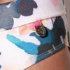 Detalle cintura lateral bañador slip Code 22 London con medallón metálico y estampado acuarela