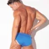 Bañador slip Code 22 Amsterdam Azul, vista frontal con manos en cintura y hebillas laterales visibles