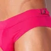 Detalle close-up hebilla metálica Code 22 grabada sobre cintura bañador slip Amsterdam Fucsia