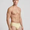 Vista lateral slip Calvin Klein Cotton Stretch crema con cinturilla a tono corte alto de pierna.